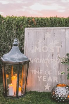 some candles are sitting on the grass near a wooden fence and a sign that says it's the most wonderful time of the year