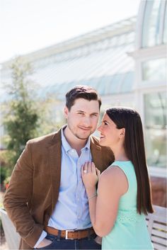 a young man and woman standing next to each other in front of a building with glass windows