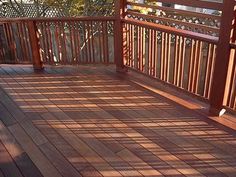 a wooden deck with railings and wood slats in the sun on a sunny day