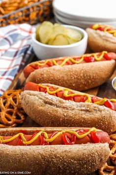 two hotdogs with mustard and ketchup on a tray next to pretzels