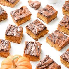 several pieces of cake sitting on top of a white surface next to a pumpkin and other dessert items