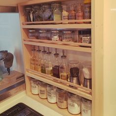 an organized spice rack in a kitchen with jars and spices on the bottom shelf, next to a stove