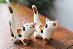 two ceramic cats sitting on top of a wooden table