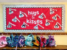 a bunch of backpacks are lined up on a shelf in front of a sign that says hugs and kisses