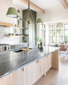 a large kitchen with marble counter tops and wooden cabinetry, along with two pendant lights hanging from the ceiling