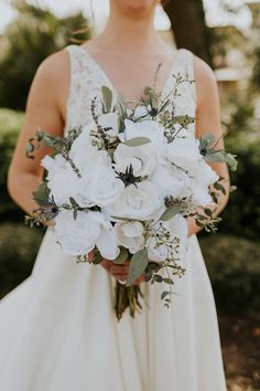 a woman holding a bouquet of white flowers