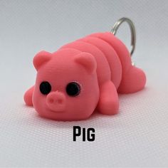 a pink pig keychain sitting on top of a white table next to a pair of scissors