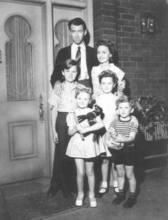 an old black and white photo of a family standing in front of a door with their children