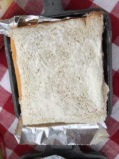 a piece of bread is sitting in a pan on a checkered tablecloth with a knife