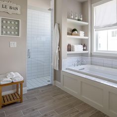 a bathroom with a large bath tub next to a walk in shower and wooden floor