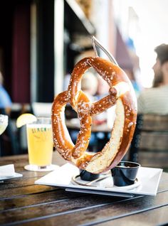 two pretzels on a table with drinks and people in the background