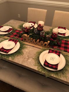 the table is set for christmas dinner with red and black plaid napkins on it