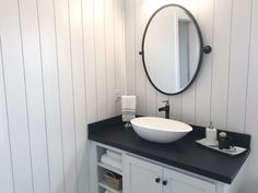 a white sink sitting under a round mirror