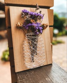 a wire vase with purple flowers in it