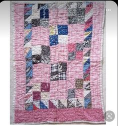 a pink and blue patchwork quilt hanging on a wall