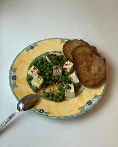 a plate with bread, peas and tofu on it