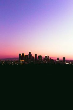 the city skyline is silhouetted against a purple and blue sky at sunset in this photo