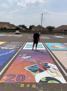 a man standing in the middle of a parking lot with lots of colorful artwork on it