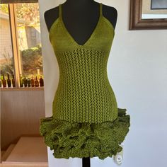 a mannequin wearing a green knitted top with ruffles on the bottom