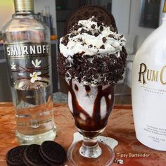 an ice cream sundae with oreo cookies and rum on the table next to it