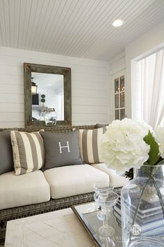 a living room filled with furniture and flowers on top of a coffee table in front of a mirror