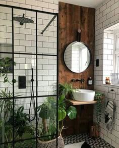 a bathroom with black and white tiled walls, a round mirror, potted plants and a sink