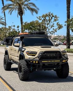 the toyota truck is driving down the street with palm trees in the backgroud