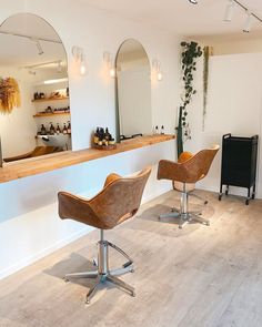 two chairs in front of a counter with mirrors and plants on the wall behind them