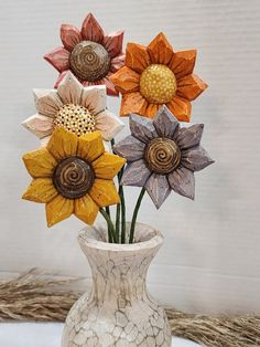 a white vase filled with colorful flowers on top of a table