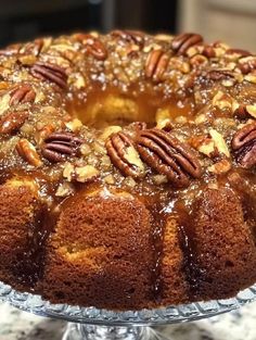 a bundt cake with pecans and caramel toppings on a glass platter