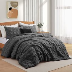 a bed with grey comforter and pillows in a room