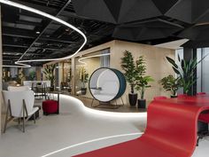 an office with black and white walls, red chairs and plants in the center area