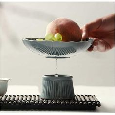 a person is pouring water into a bowl with fruit in it on top of a table