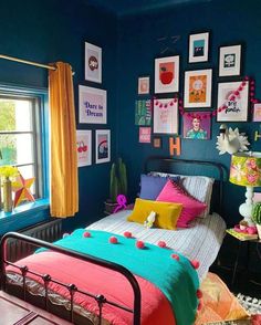 a bedroom decorated in bright colors with pictures on the wall and colorful bed linens