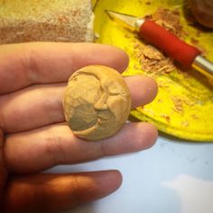 a person holding a rock in their hand with a knife on the table behind it