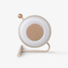 a white cup and saucer on a wooden stand with a gold ball in the middle