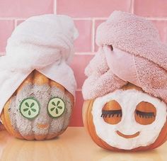 two pumpkins with faces painted to look like they are wearing towels on their heads