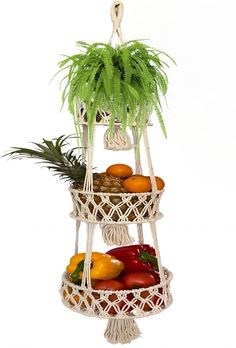 three tiered fruit basket with plants and fruits in it on a white stand against a white background