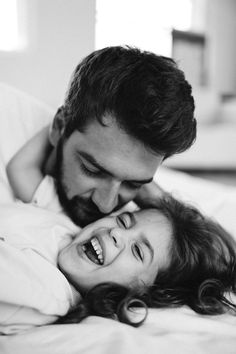 a man and woman laying on top of a bed with their heads touching each other