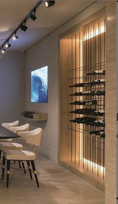 a dining room table with white chairs and lights on the wall next to wine racks