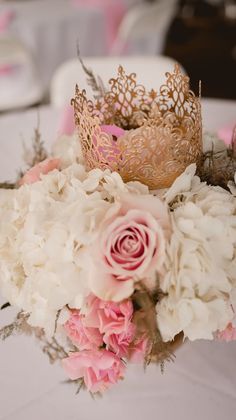 a bouquet of flowers with a crown on top is sitting on a white tablecloth