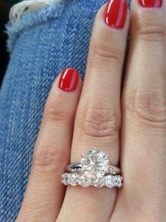 a woman's hand with a red manicured nail polish and two engagement rings