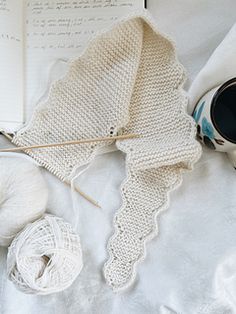 an open book and some yarn on a bed