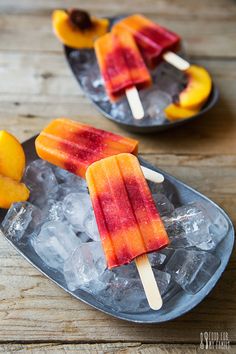 two popsicles with fruit on them sitting on ice