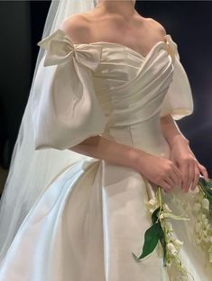 a woman in a white wedding dress holding flowers