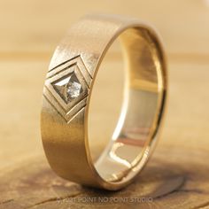 a wedding ring with a diamond in the center on a wooden surface, close up