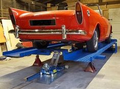 an orange car is being worked on in a garage