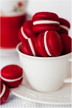 red velvet macaroons in a white bowl on a plate next to some cookies