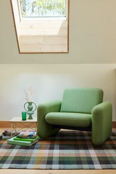 a green chair sitting on top of a wooden floor next to a table and lamp