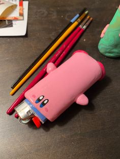 a pink pig shaped pencil holder next to some colored pencils